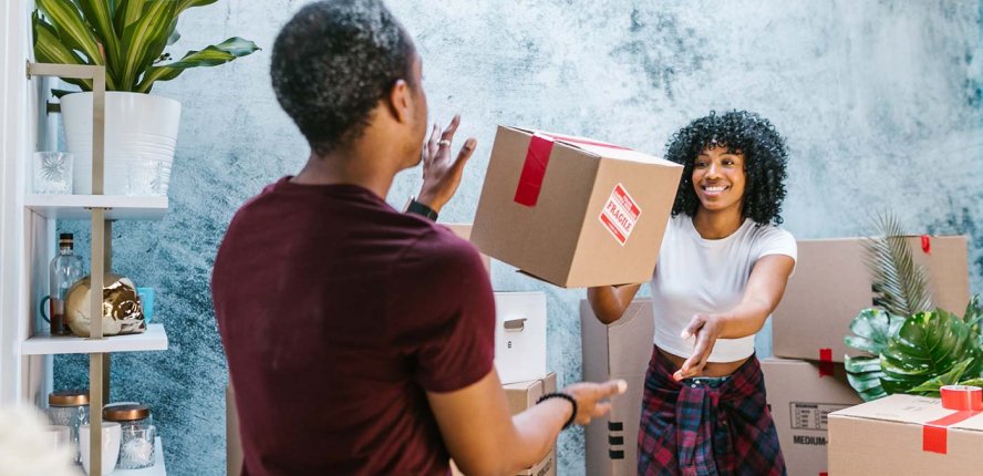 Happy couple moving boxes in a home setting, showcasing the excitement of house removals and