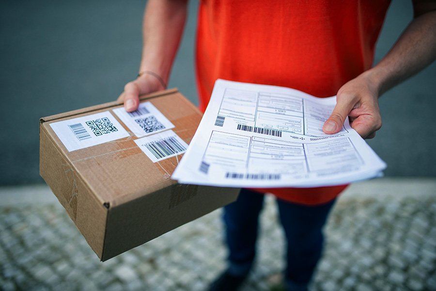 Person holding a cardboard package and shipping documents, representing Aus City Movers' parcel delivery service