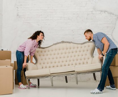 Couple lifting a vintage sofa surrounded by moving boxes, illustrating Aus City Movers' furniture moving