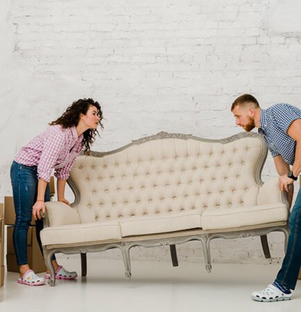 Couple lifting a vintage sofa surrounded by moving boxes, illustrating Aus City Movers' furniture moving