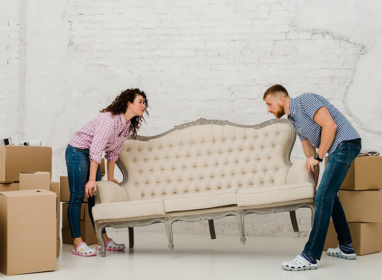 Couple lifting a vintage sofa surrounded by moving boxes, illustrating Aus City Movers' furniture moving