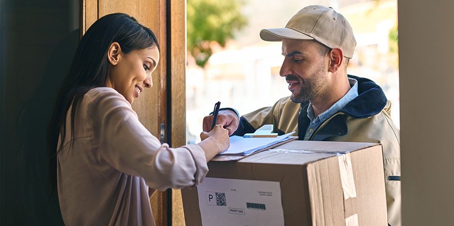 Woman signing for a parcel delivery from a delivery person at the door, illustrating Aus