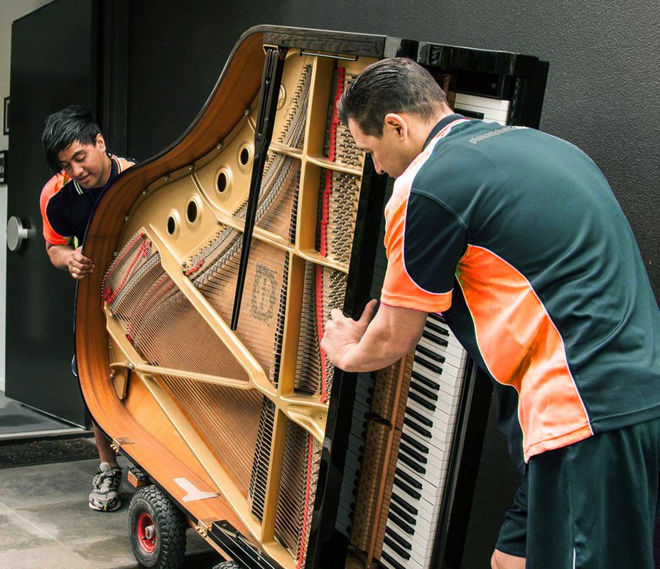 Aus City Movers team carefully moving a grand piano with specialized equipment.